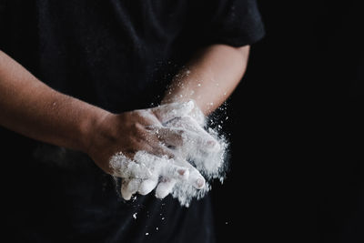 Close-up of hand holding leaf against black background