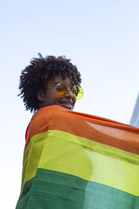 Young man with afro hair in the city with the pride flag