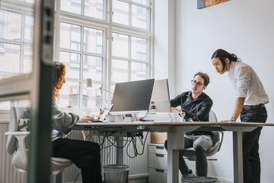 Businessmen discussing over desktop pc at desk in office