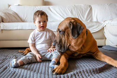 Disabled boy with dog sitting on carpet at home