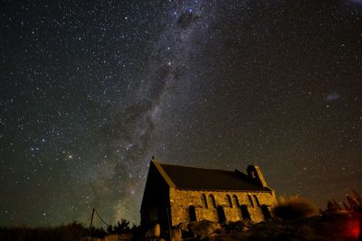 Built structure on landscape against stars at sky