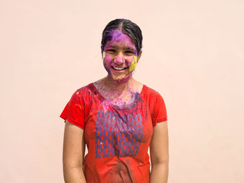 Portrait of young woman standing against wall