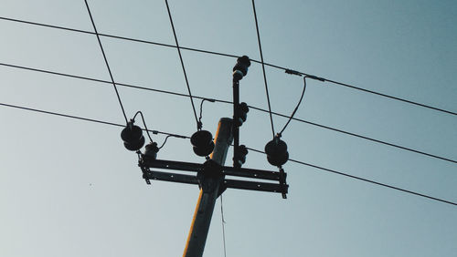 Low angle view of birds on cable against sky
