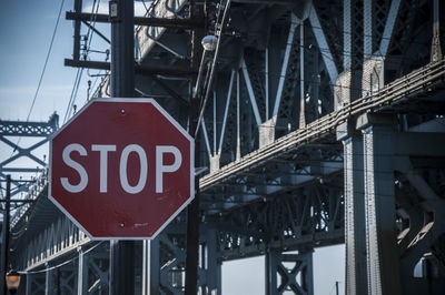 Close-up of stop sign against bridge