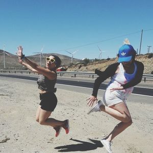 Full length of friends playing on beach against clear sky