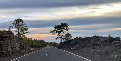 Road amidst trees against sky during sunset