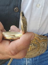 Midsection of person holding gold colored pocket watch