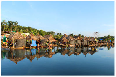 Reflection of huts in lake against sky