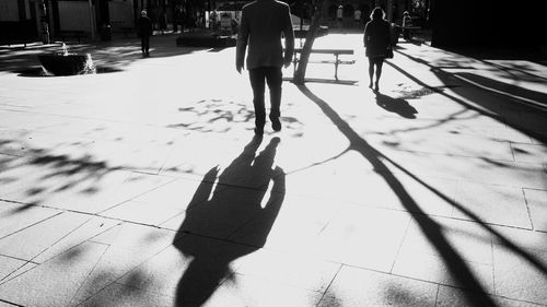 Shadow of people walking on footpath