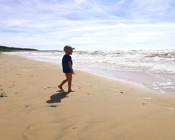 Cute boy walking on sand at beach