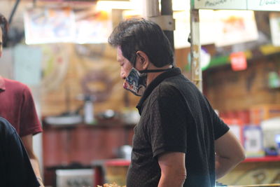 Side view of young man standing at store