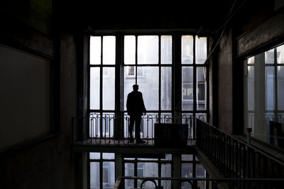 Silhouette man standing by window