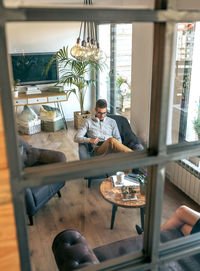 High angle view of young man using phone by woman sitting at table