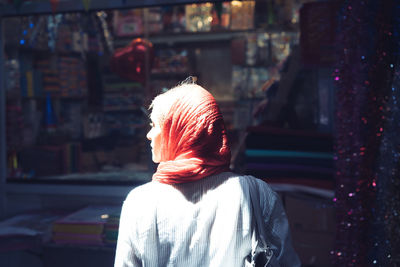 Rear view of woman with umbrella standing against built structure
