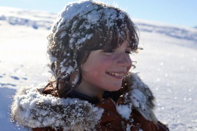 Close-up of smiling boy with snow on head during winter