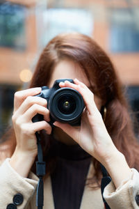 Portrait of woman photographing with camera in city