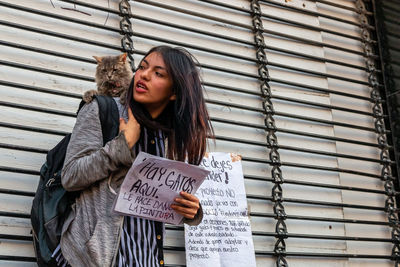 Young woman standing against metal grate