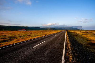 Road amidst field against sky