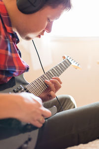 Midsection of man playing guitar at home