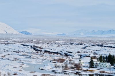 Scenic view of lake by snowcapped mountains against sky