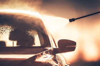Silhouette pipe spraying water on car during sunset