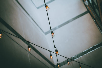 Low angle view of illuminated pendant light hanging on ceiling