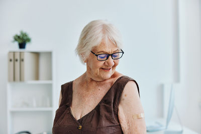Smiling senior woman with bandage on arm at hospital