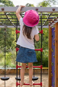 Rear view of girl climbing jungle gym in park