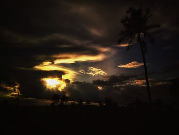 Low angle view of silhouette trees against dramatic sky