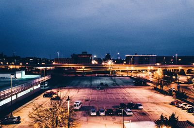 High angle view of cars on street in illuminated city against sky at dusk