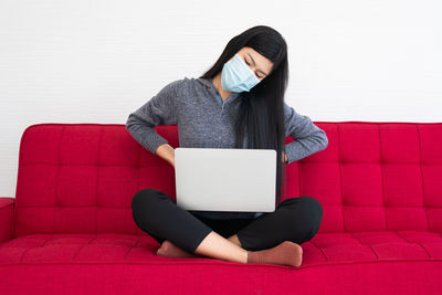 Woman using phone while sitting on sofa