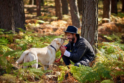 Portrait of young tattoed man with his dog in the forest