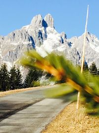 Road leading towards mountains against blue sky