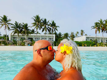 Midsection of friends in swimming pool against sky