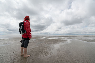 Rear view of person on beach against sky and wadden sea