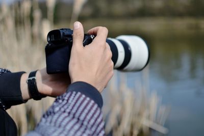 Midsection of man photographing by lake