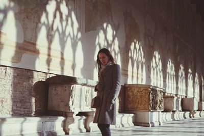 Portrait of woman standing against wall