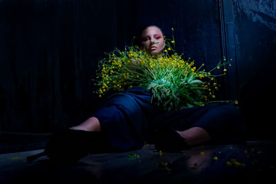 Young woman sitting with plant at night