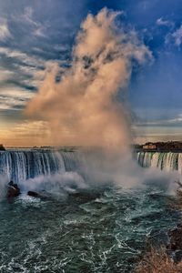 View of waterfall against cloudy sky