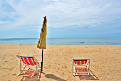 Chair on beach against sky