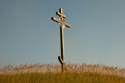 Low angle view of cross on field against clear sky