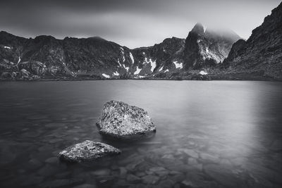 Scenic view of rocks in sea against mountains