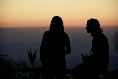 Silhouette people standing against sky during sunset