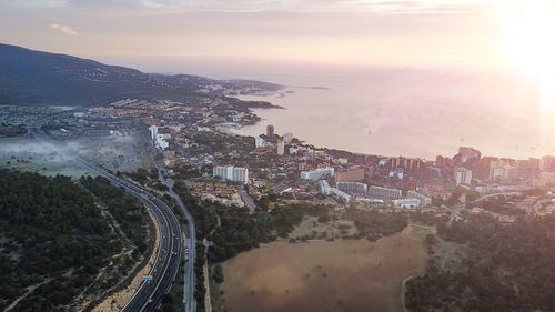 High angle view of town by sea against sky during sunset