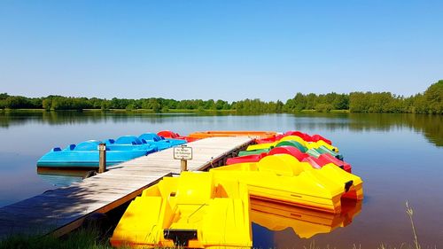 Boat moored in lake against clear blue sky