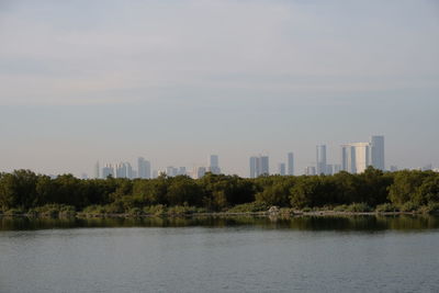 Scenic view of lake by buildings against sky