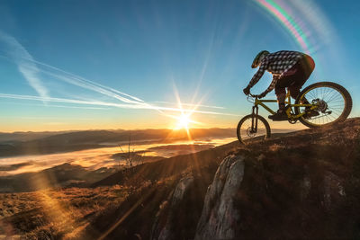 Bicycle on land against sky during sunset