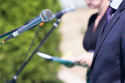 Midsection of businessman standing by microphone
