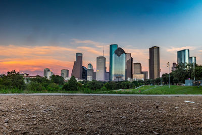 Modern buildings in city against sky during sunset