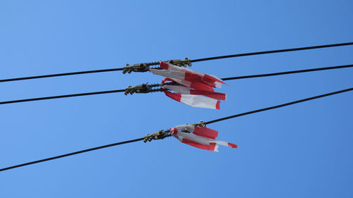 Low angle view of flags hanging against clear blue sky